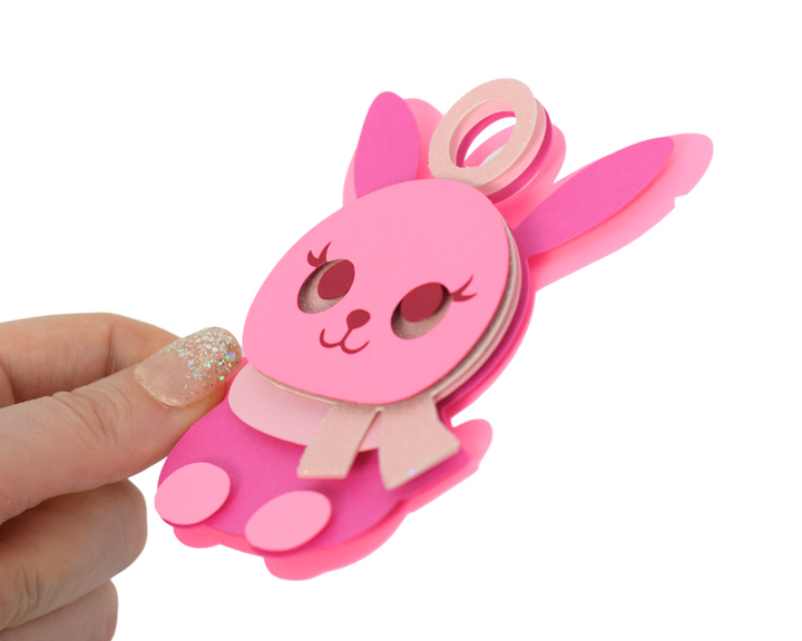 a hand holding a pink toy with a bunny on it