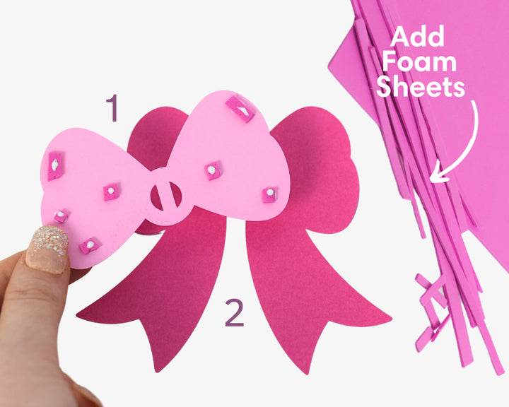 a hand holding a pink paper cut out of a bow