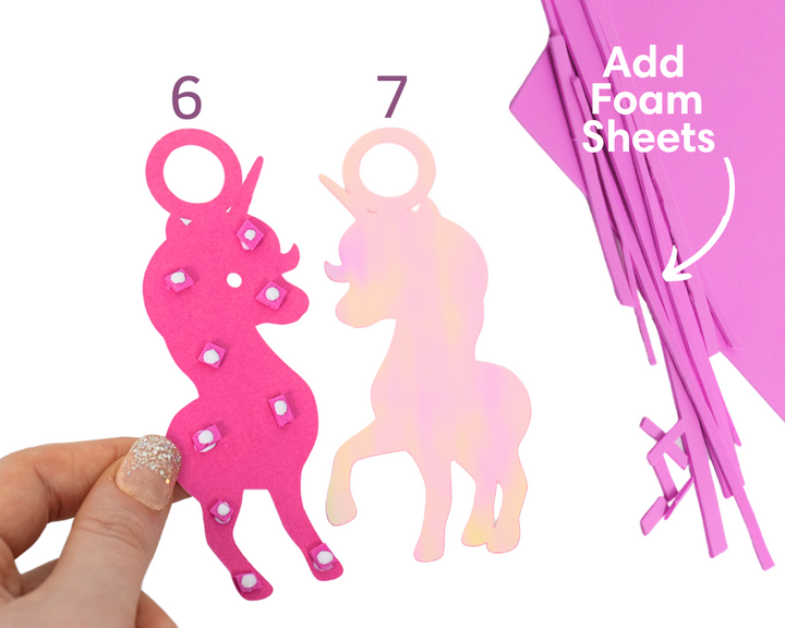 a hand holding a pink paper cut out of a horse