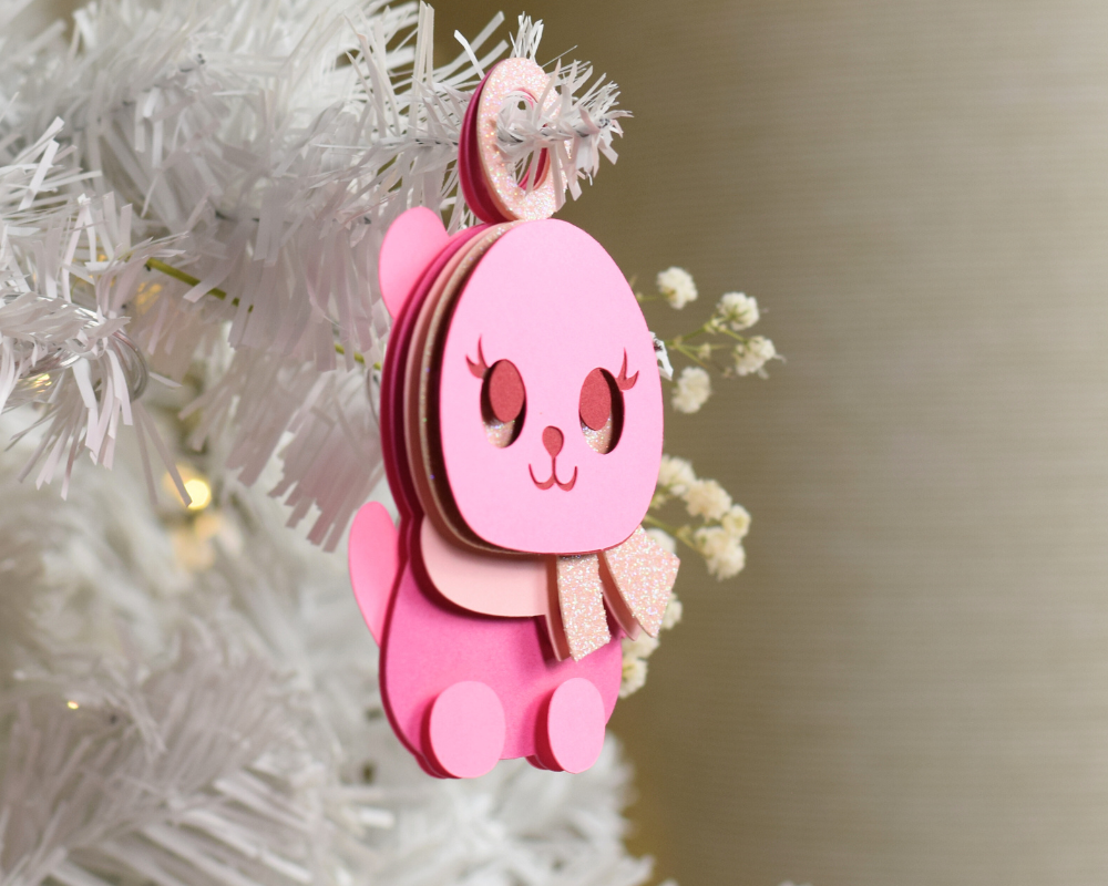 a pink ornament hanging from a white christmas tree