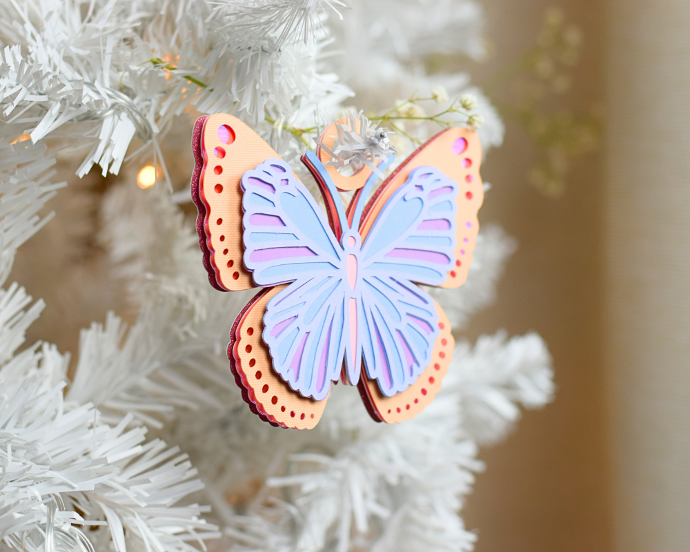 a blue butterfly ornament hanging from a white christmas tree