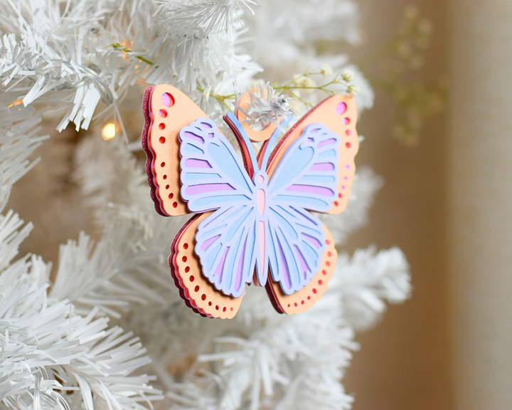 a blue butterfly ornament hanging from a white christmas tree