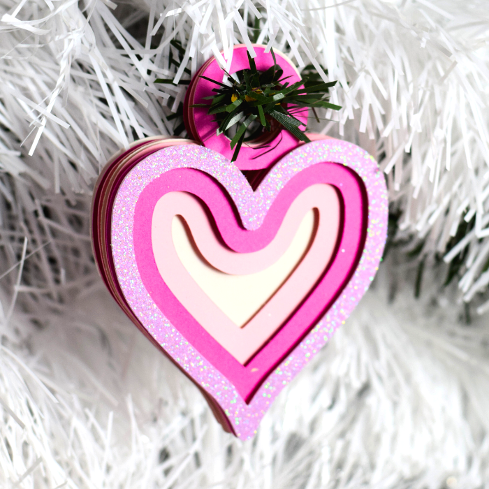 a heart shaped ornament hanging from a christmas tree