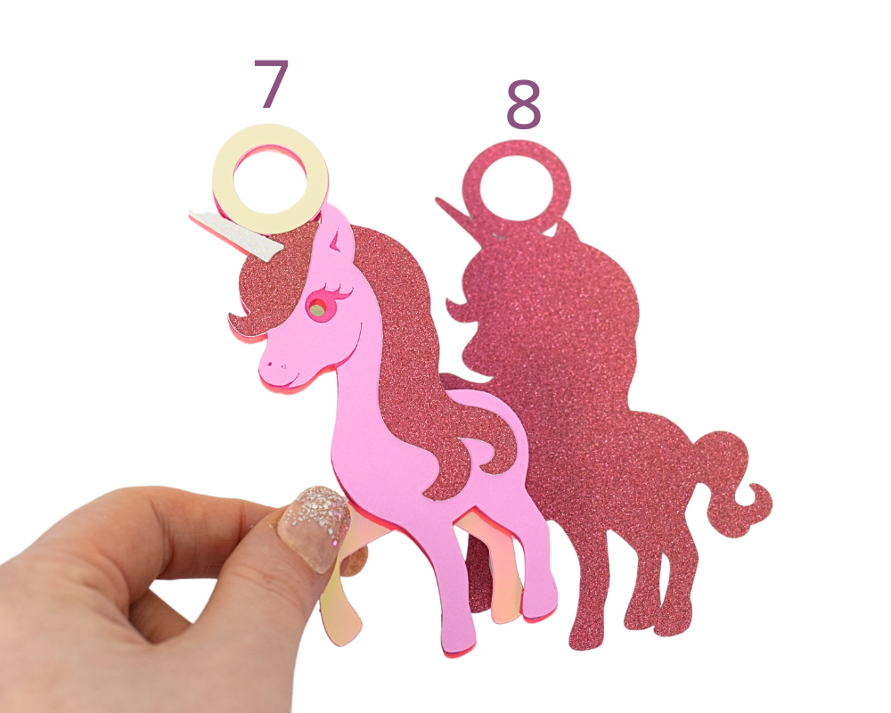 a hand holding a pink unicorn cut out of paper