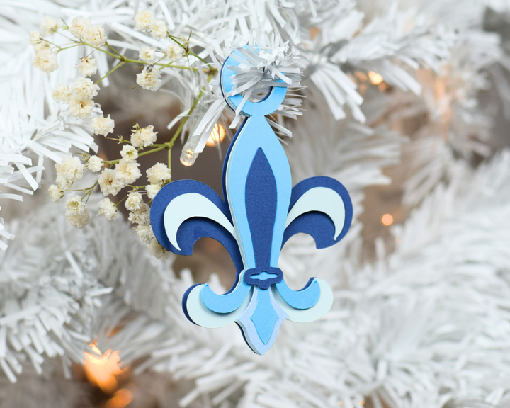 a blue and white fleur de lis ornament hanging from a christmas