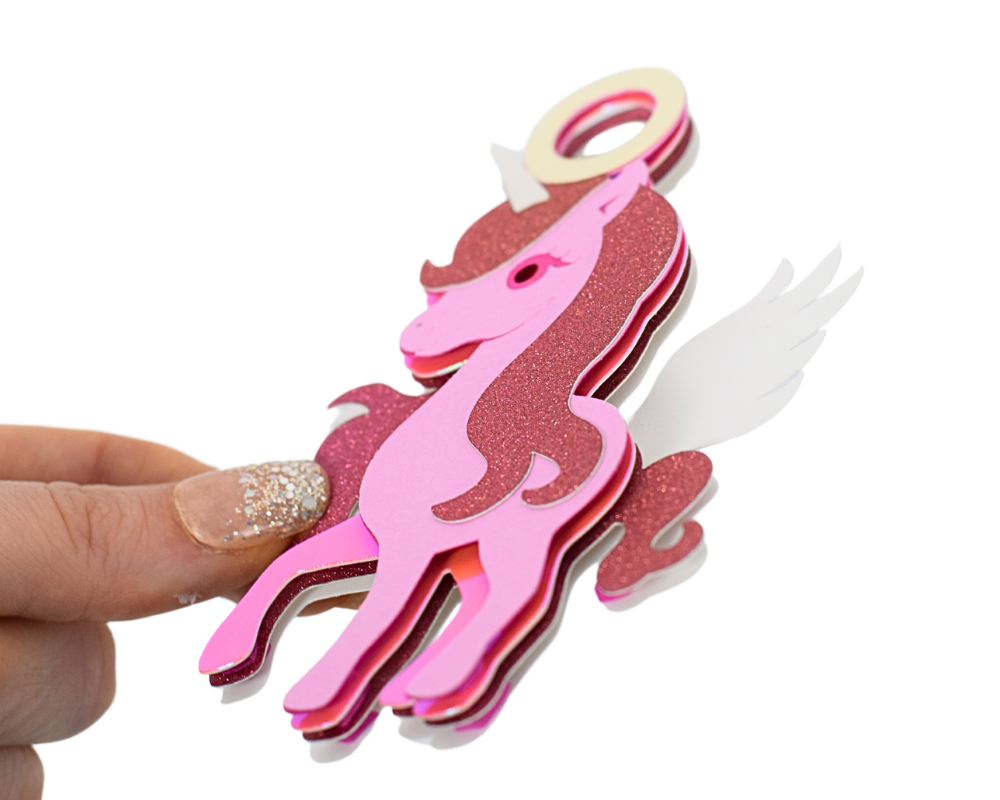 a hand holding a pink and white paper cut out of a horse