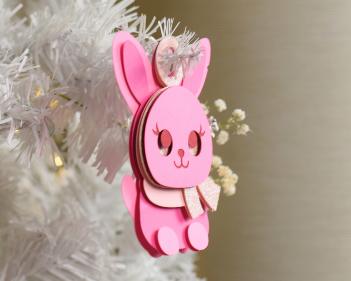 a pink ornament hanging from a white christmas tree