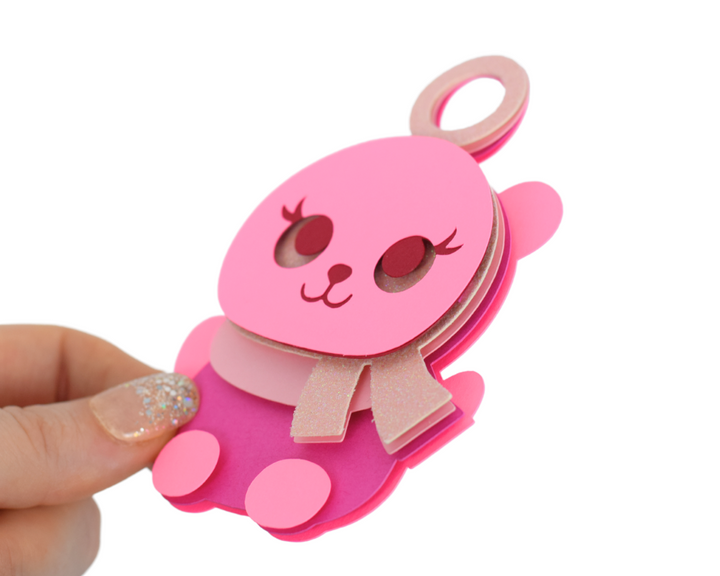 a hand holding a pink bear shaped key chain