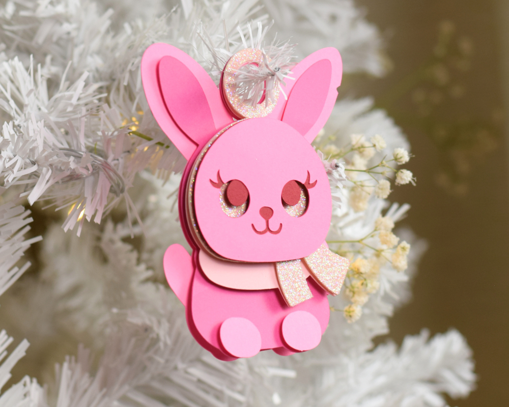 a pink ornament hanging from a white christmas tree