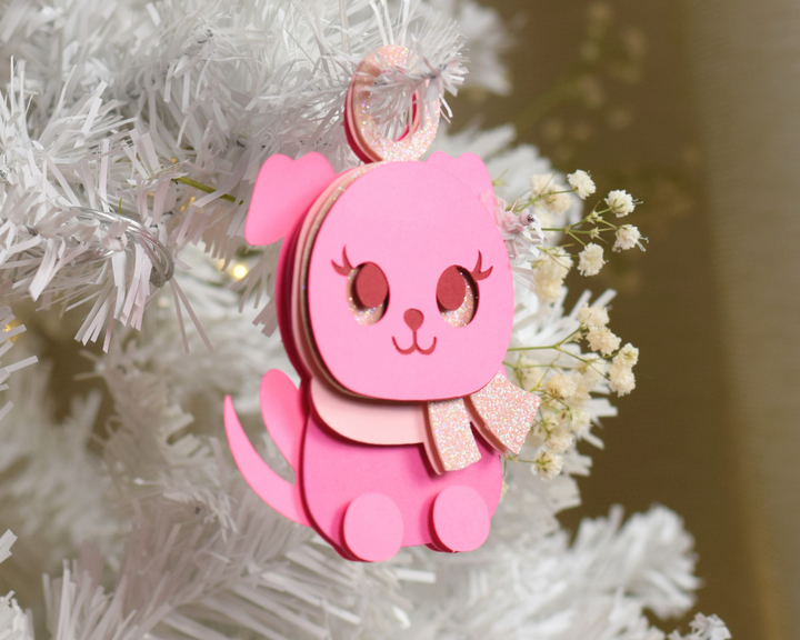 a pink ornament hanging from a white christmas tree