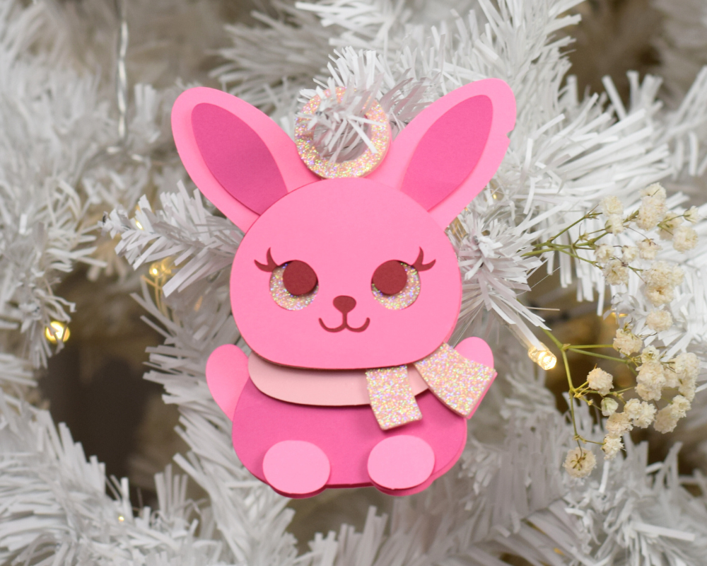 a pink ornament hanging from a white christmas tree