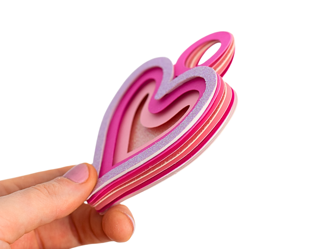 a hand holding a pink and purple heart shaped object