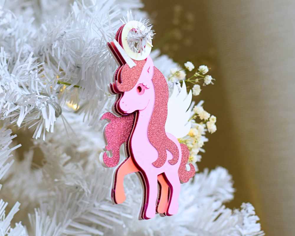 a pink christmas ornament hanging from a white christmas tree