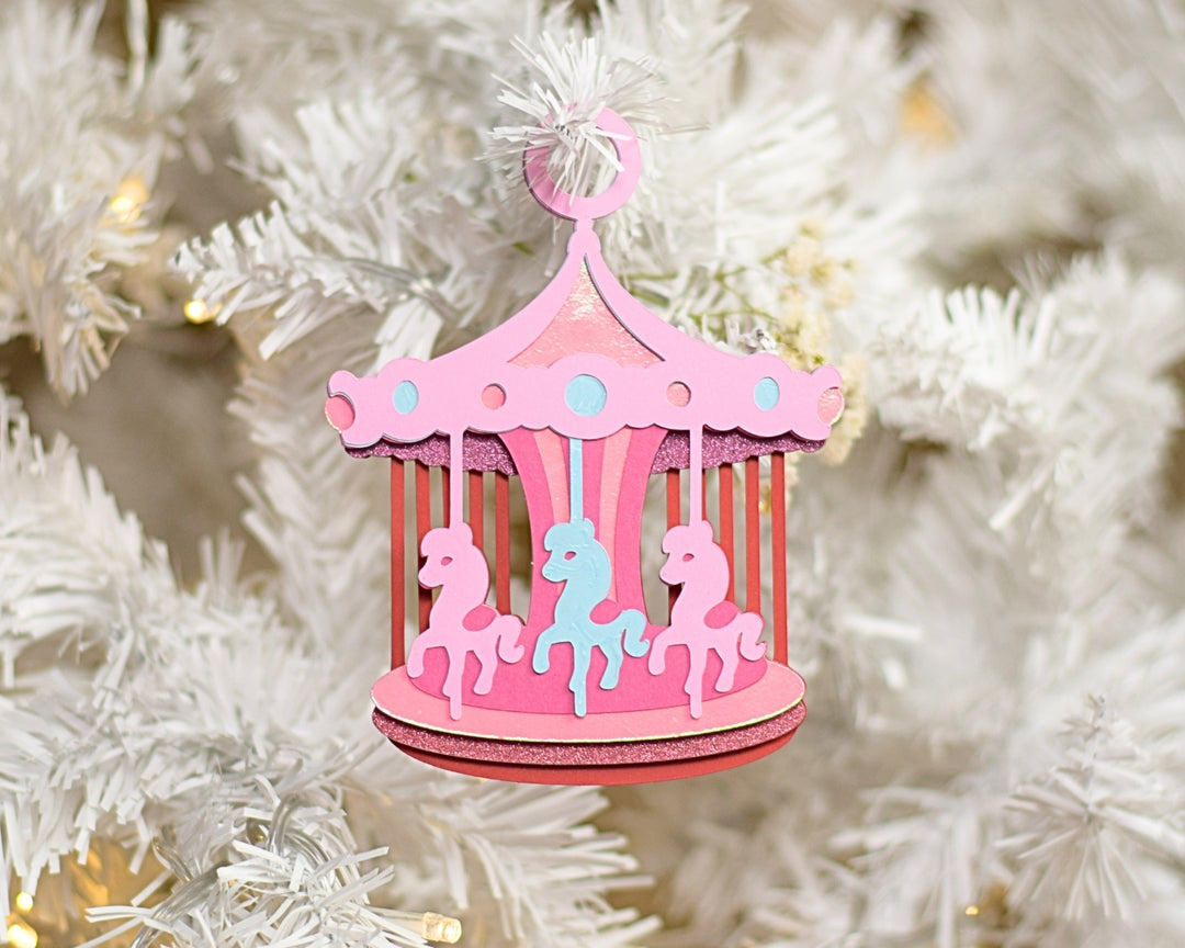 a pink carousel ornament hanging from a christmas tree