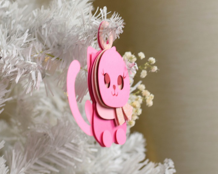 a pink ornament hanging from a white christmas tree